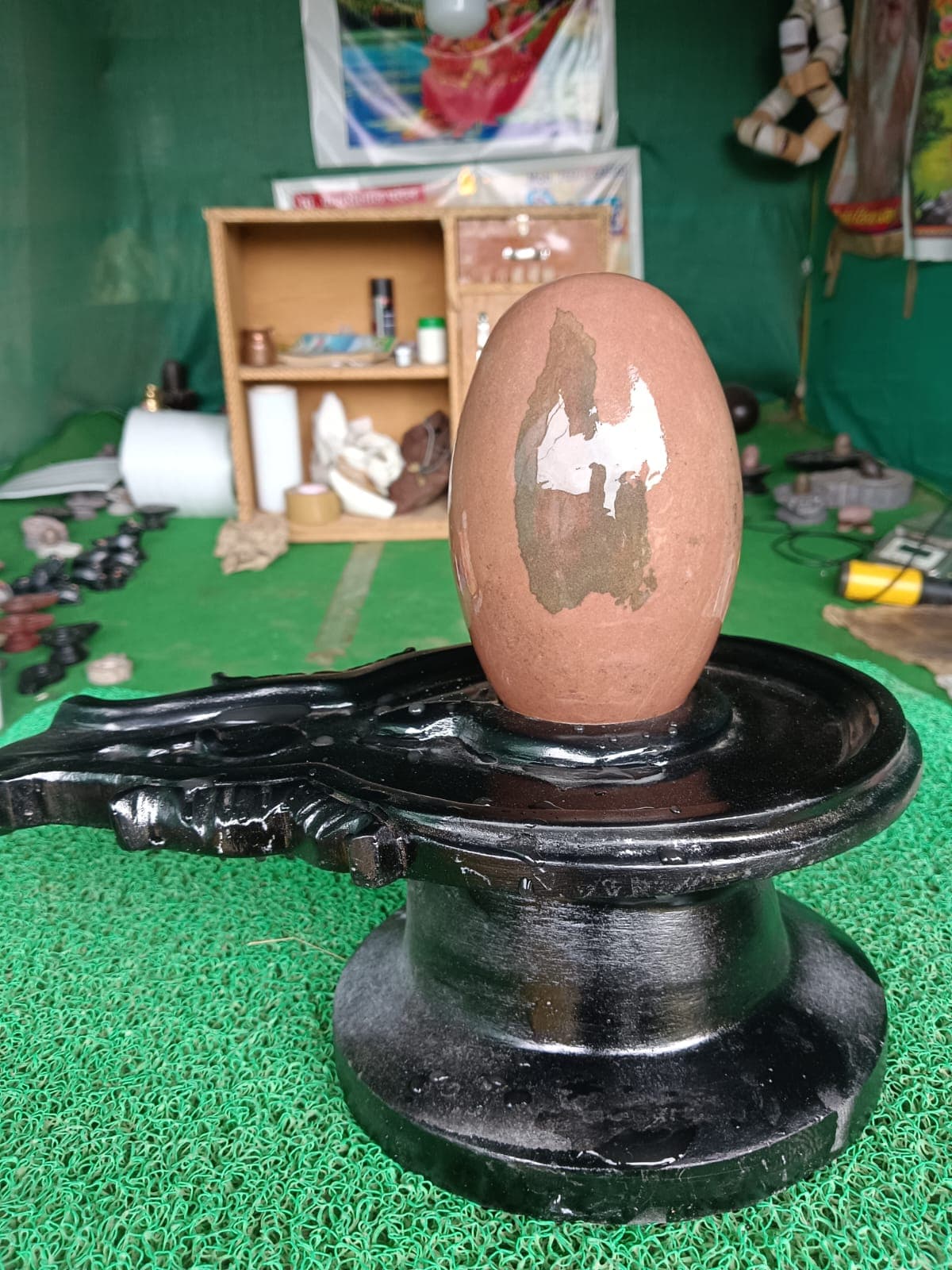 Authentic Narmadeshwar Shivling in reddish-brown Narmada stone mounted on a polished black granite yoni pitha