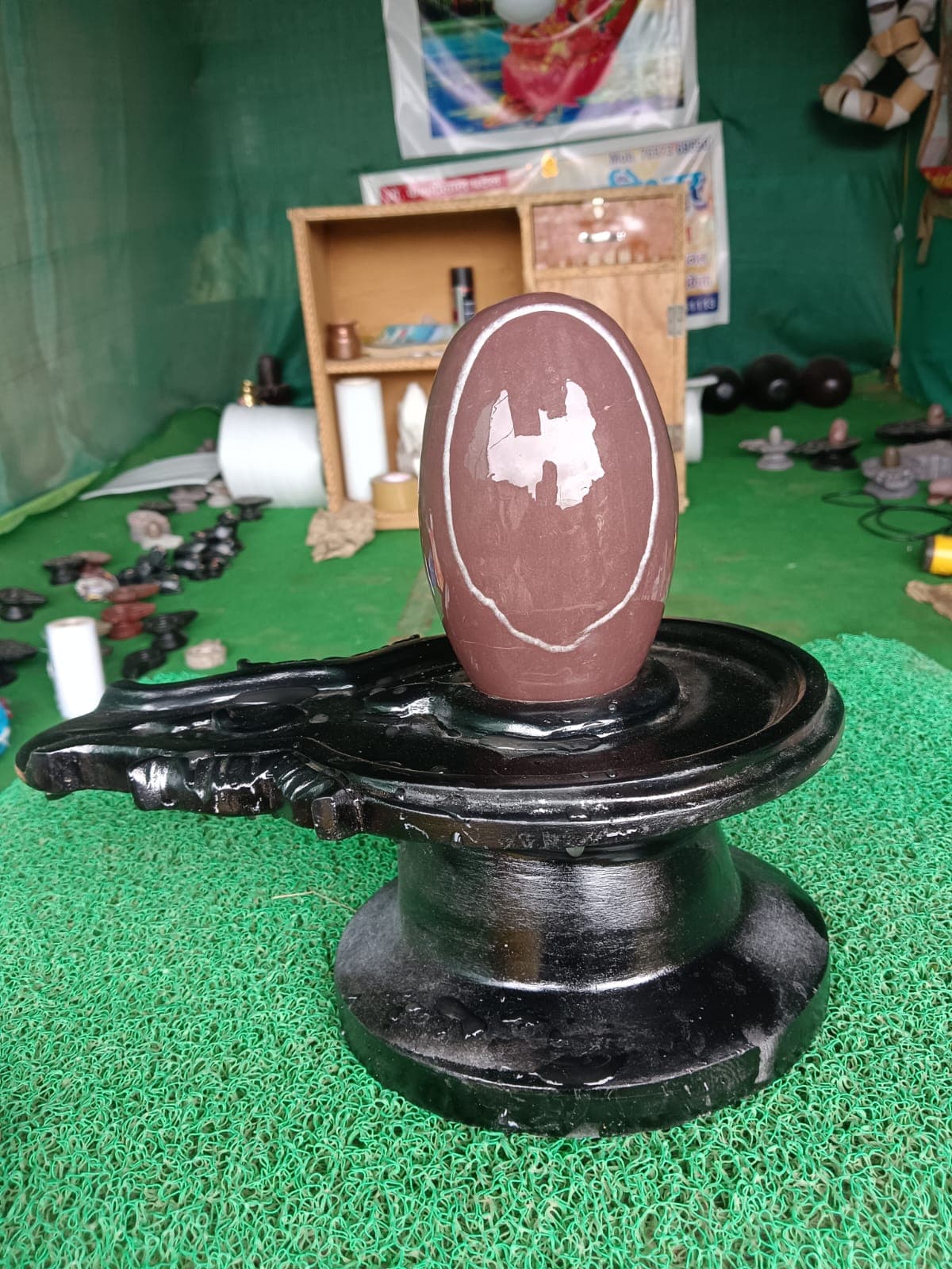 Rose-brown Narmadeshwar Shivling with a distinct white oval ring marking, on a black stone base
