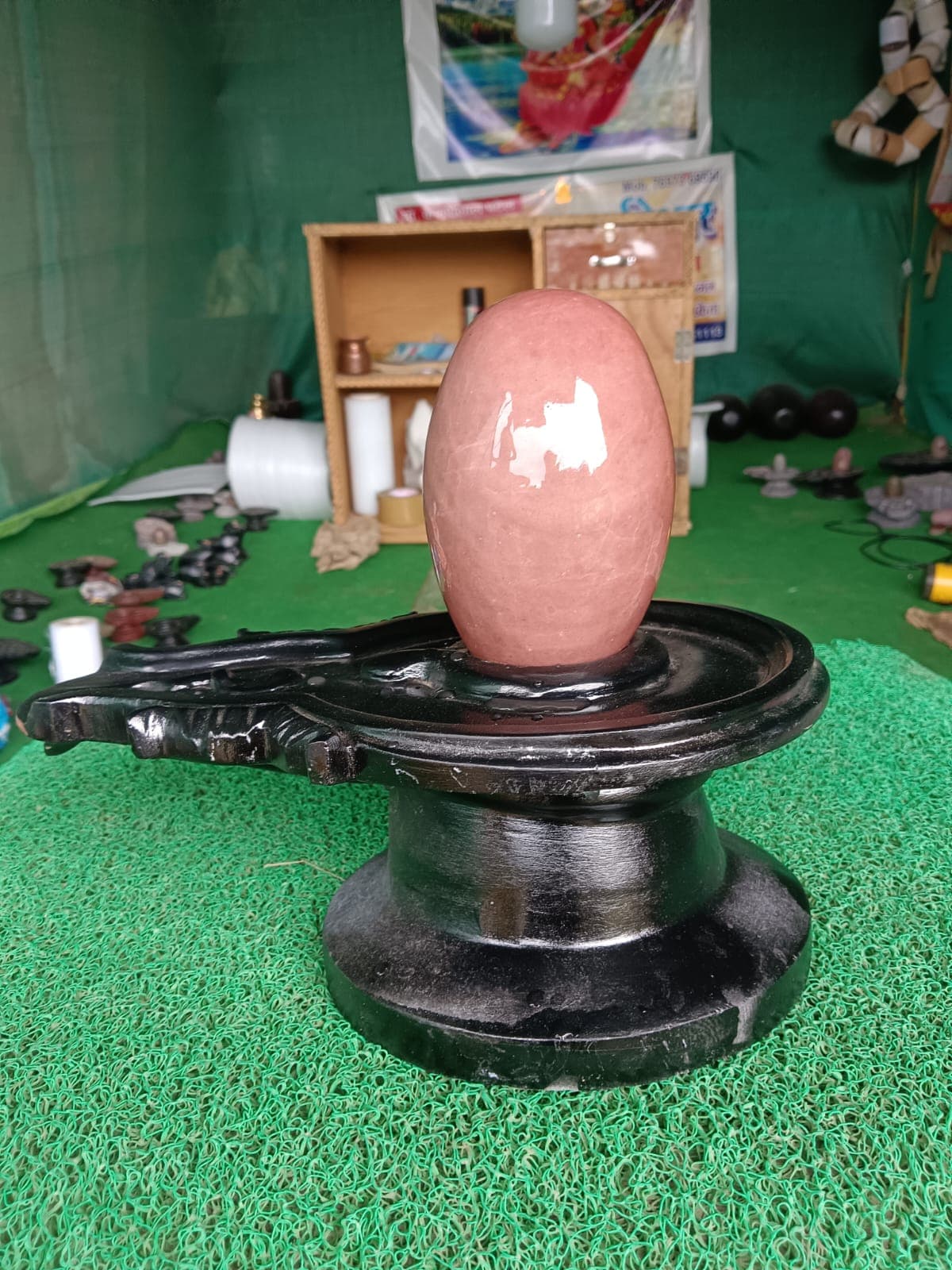 Smooth salmon-pink Narmadeshwar Shivling, an unmarked natural Narmada bana linga on a black base